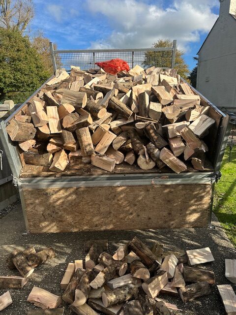 A trailer piled high with freshly split hardwood logs